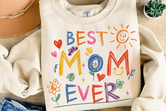 Cream-colored crewneck sweatshirt with "Best Mom Ever" written in colorful crayon-style letters surrounded by hearts, a sun, and flowers.