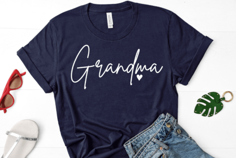 T-shirt with the word “Grandma” in cursive lettering and a small heart accent, available in various colors.