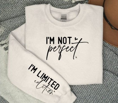 White crewneck sweatshirt with the text 'I'M NOT PERFECT' on the front and 'I'M LIMITED EDITION' on the sleeve, displayed on a grey background.