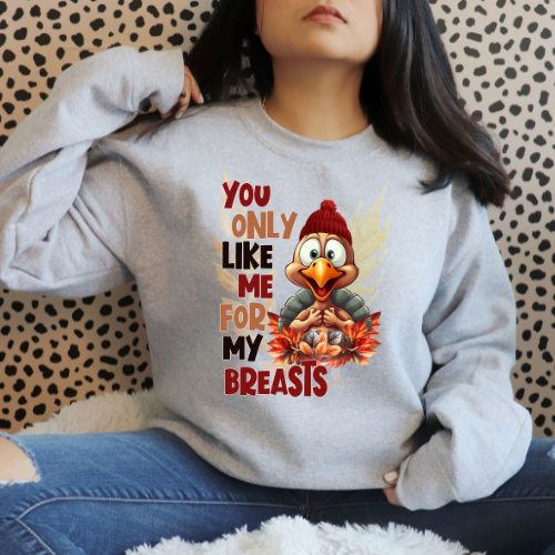 Person wearing a gray sweatshirt with a cartoon character and text, sitting against a patterned wall.