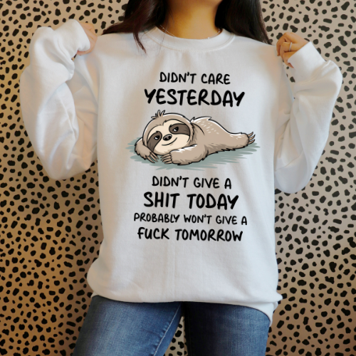 Person wearing a white sweatshirt with a sloth graphic and text on a patterned background