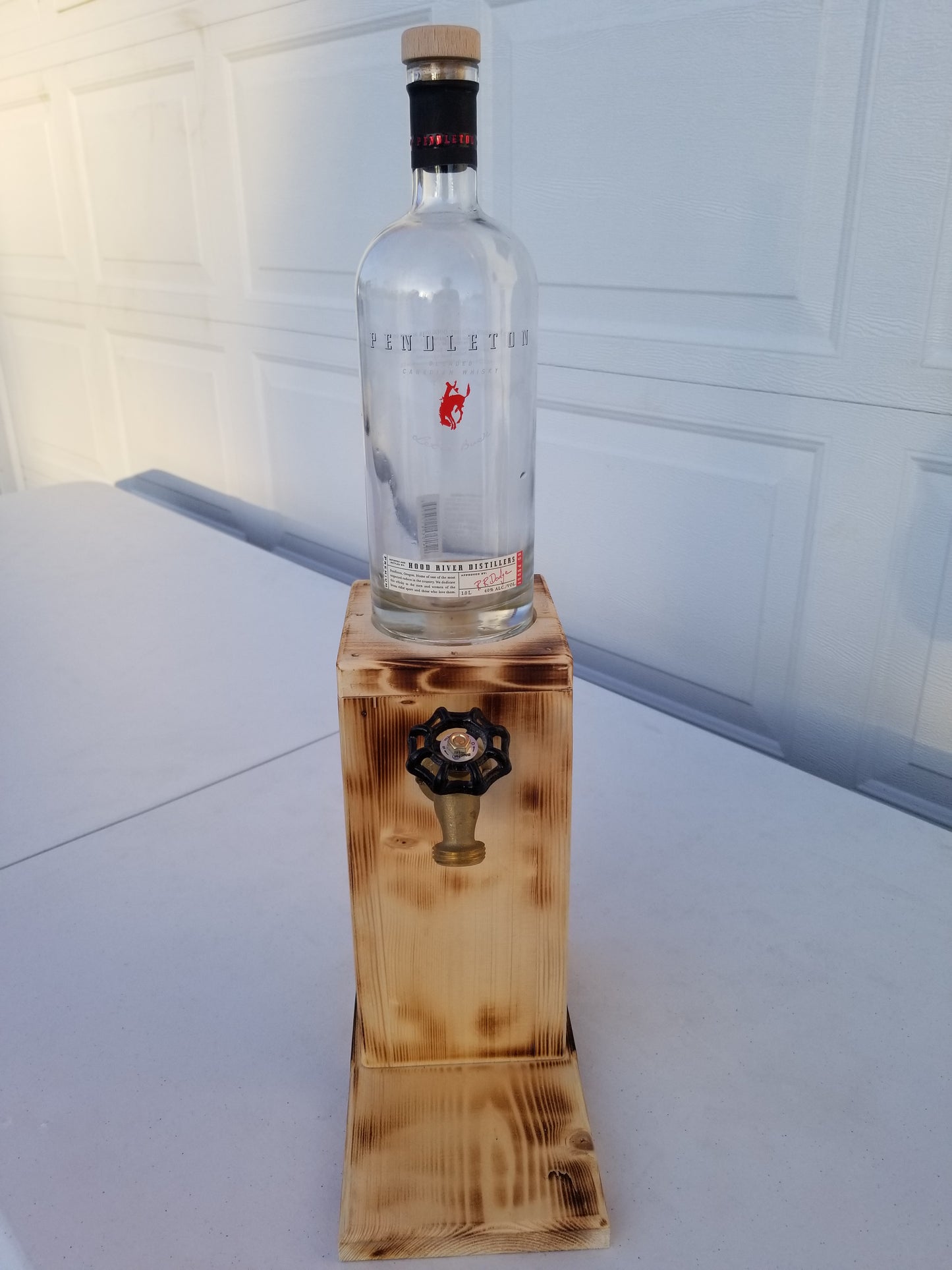 Rustic Pendleton liquor dispenser with permanent bottle, spigot, and refill funnel.