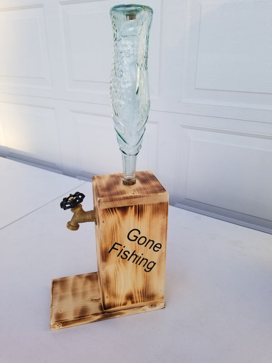 A custom fish bottle with a wooden base, labeled 'GONE FISHING', designed to resemble a fish, primarily used as a liquor dispenser.