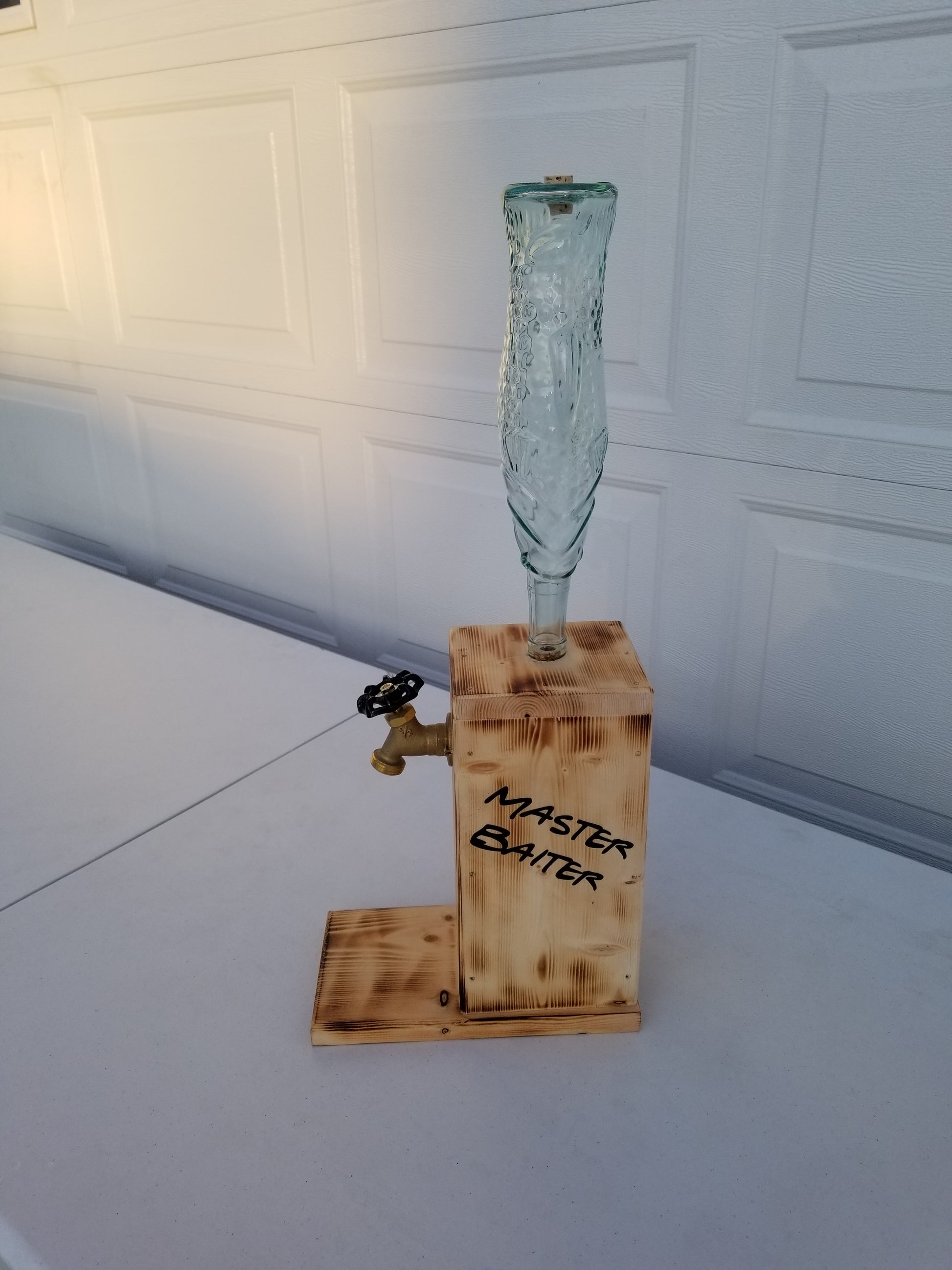 Liquor dispenser with fish-shaped bottle and ‘Master Baiter’ burned on both sides.