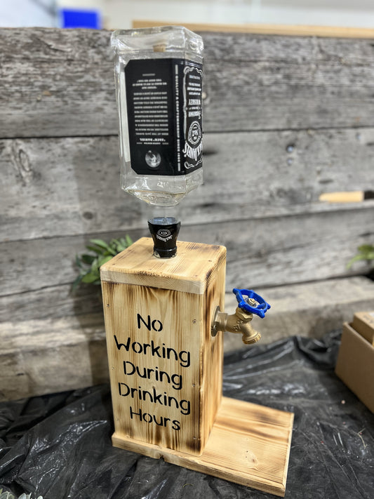 A custom wooden liquor dispenser with a 'No working during drinking hours' sign, mounted on a bottle holder.