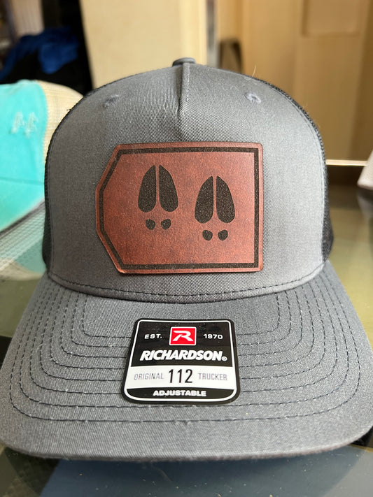 A gray Richardson snapback hat with a leather patch featuring elk footprints design on the front.