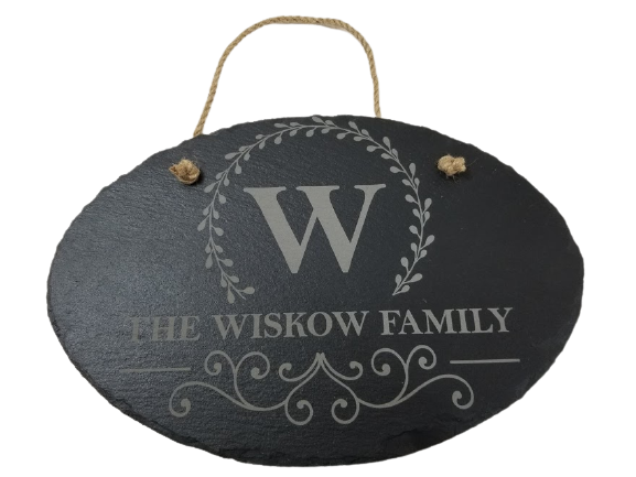 A slate door hanger with an engraved initial and the phrase 'THE WISKOW FAMILY' surrounded by a floral wreath design.