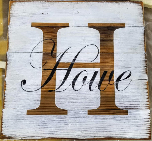 A white wooden monogram sign with the letter 'H' and Howe black script, mounted on a wall.