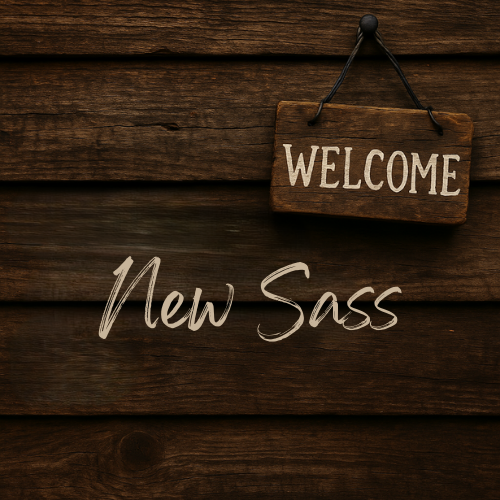 Rustic wooden sign hanging on a dark wood wall with the words “New Sass” in bold white letters, representing the Red Barn 94 New Arrivals collection of snarky shirts, mugs, and unique gifts.