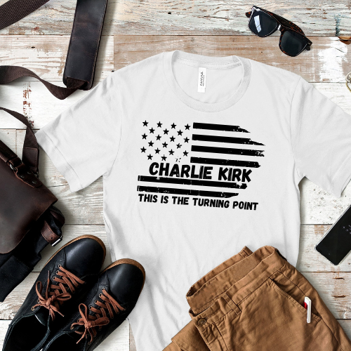 White t-shirt with 'Charlie Kirk This is the Turning Point' design on a wooden surface with shoes and pants.