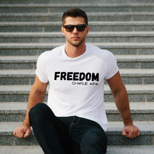 Man wearing a white t-shirt with 'FREEDOM CHARLIE KIRK' text sitting on steps.