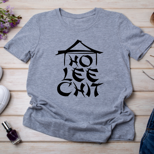 Gray t-shirt with 'HO LEE CHIT' graphic on a wooden surface