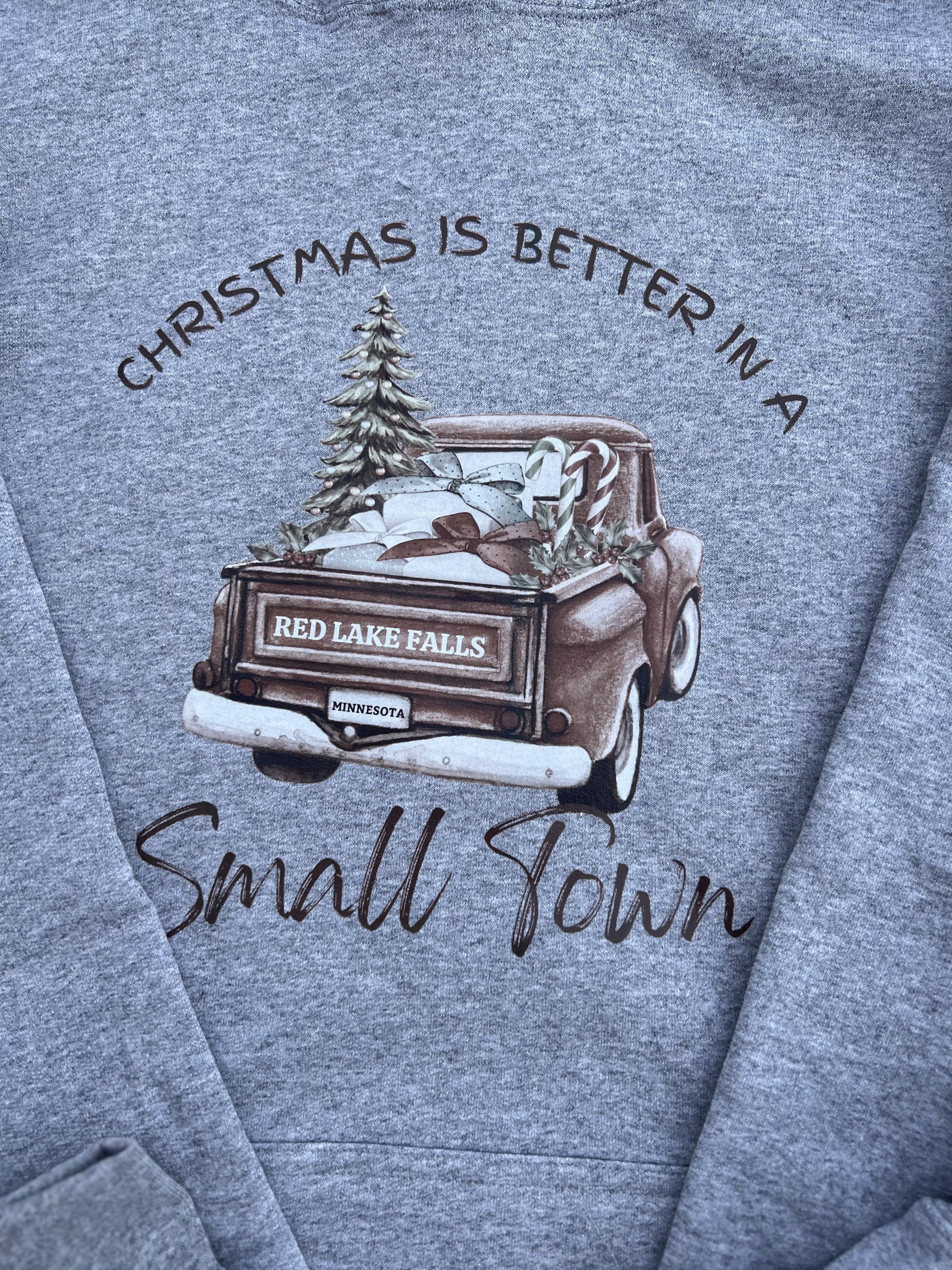 Gray sweatshirt with a graphic of a truck and text 'Christmas is better in a small town' on a blue background