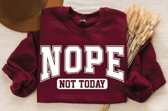 Maroon sweatshirt with 'NOPE NOT TODAY' text on a light wooden surface.