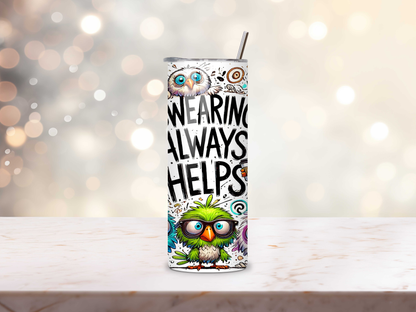 Tumbler with bird design and text on a wooden surface with blurred lights in the background